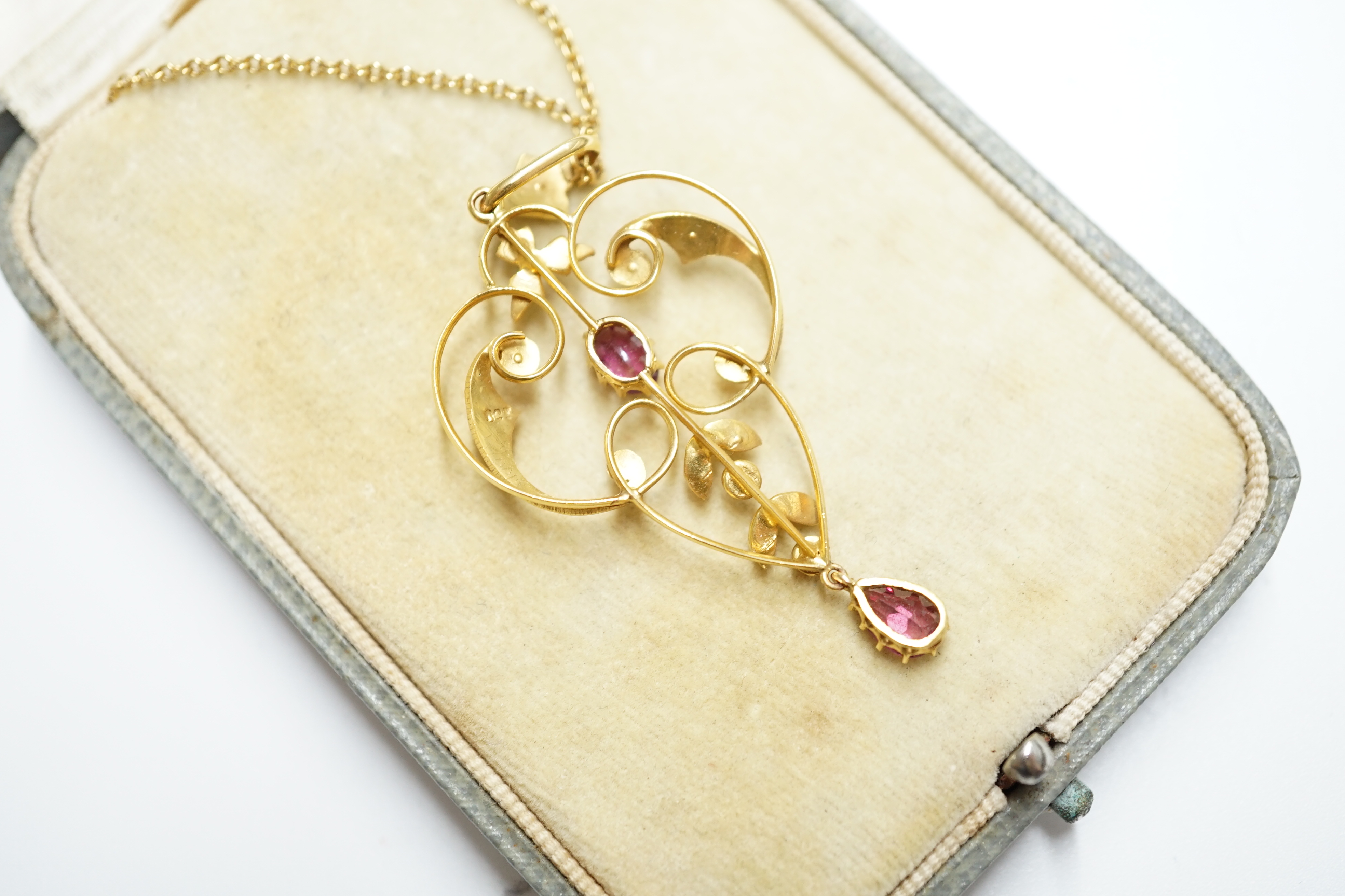 A cased Edwardian 9ct, garnet and seed pearl cluster set drop pendant, 52mm, on a yellow metal fine link chain, 40cm, gross weight 4.7 grams. Condition - fair to good